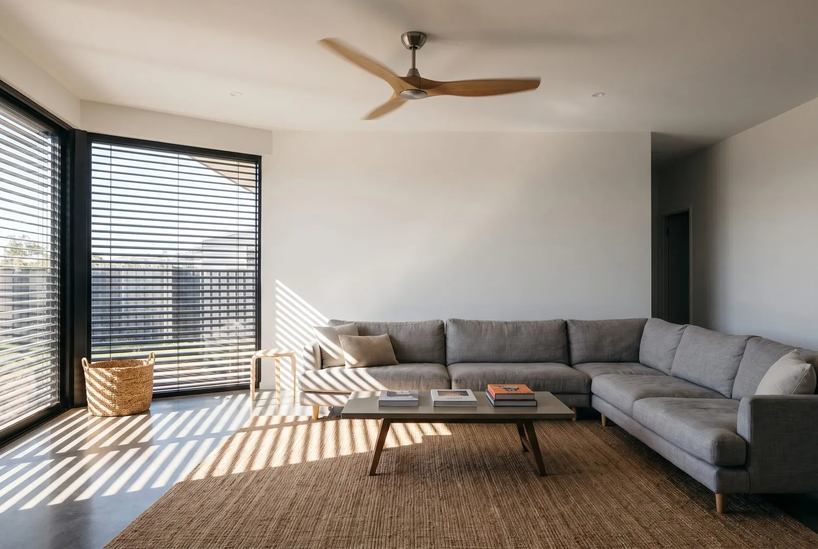 Ceiling fan over a living room with the blinds half closed